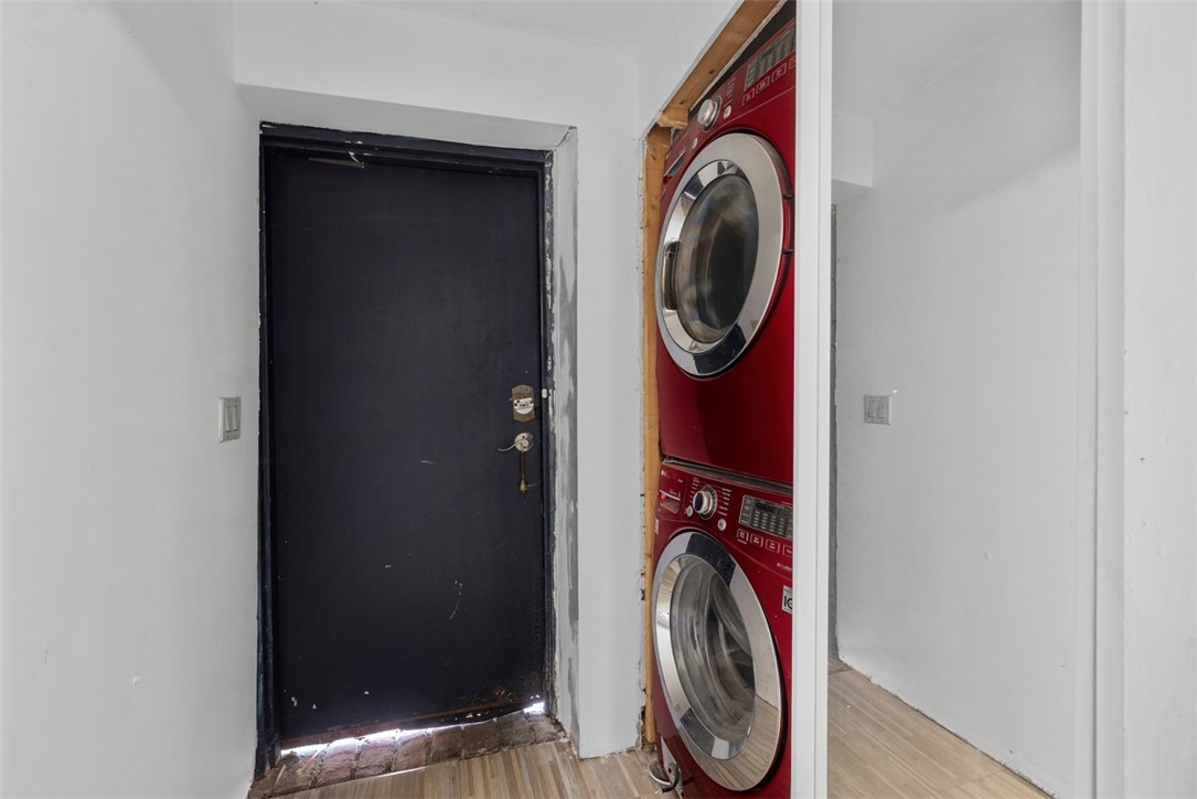 Entry hallway with a black door beside a red stacked washer and dryer.