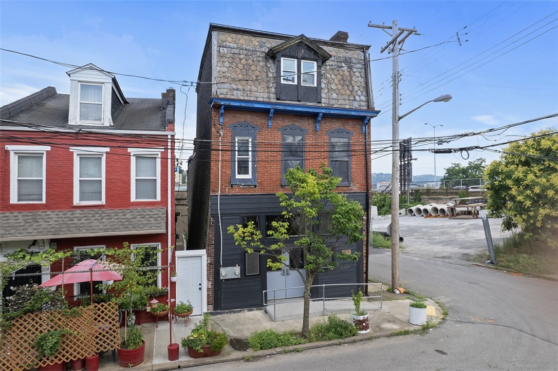 Narrow brick building with a shingled upper story and dark-painted ground floor