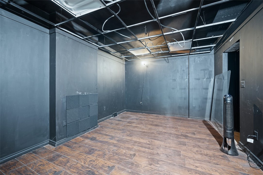 Empty room with dark gray walls, wood-look flooring, and an exposed ceiling.