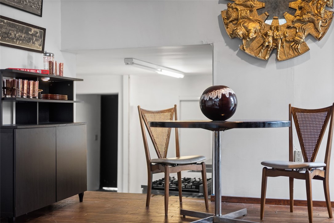 Dining area with a round black table, cane-back chairs, and a gold wall sculpture.