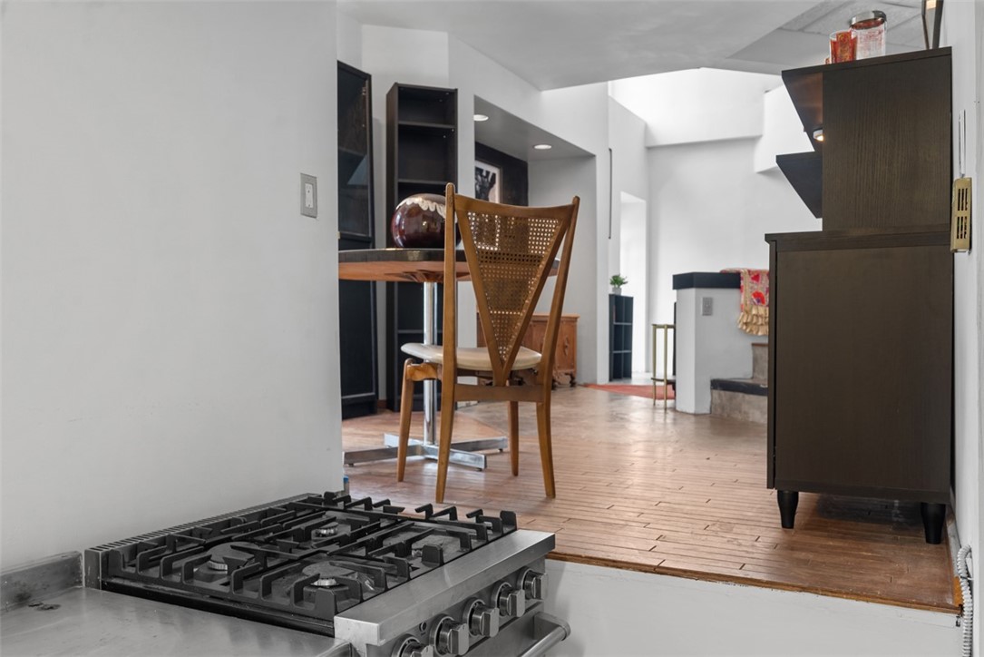 Kitchen with a stainless-steel gas cooktop in the foreground and a wood dining table beyond.