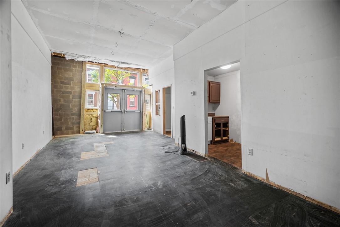 Unfinished interior with exposed brick, double entry doors, and a small kitchenette.
