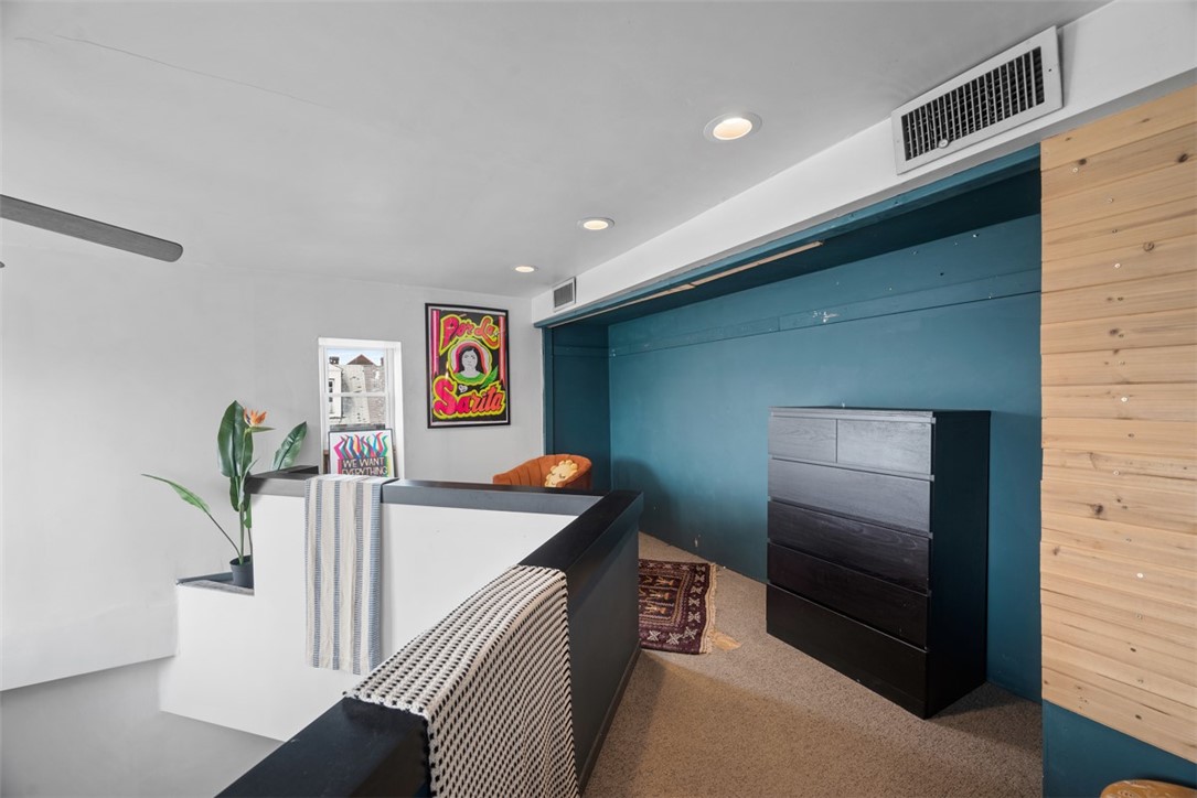 Bedroom with a teal accent wall, dark dresser, and white partition with black trim.