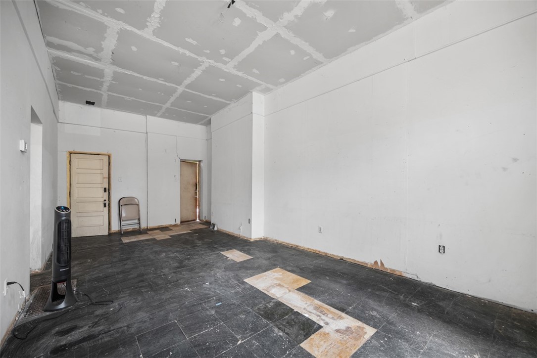 Unfinished room with patched dark flooring and an incomplete drywall ceiling