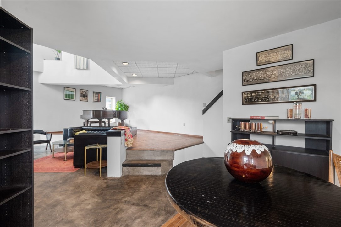 Loft living area with a raised wood platform, grand piano, and leather seating.