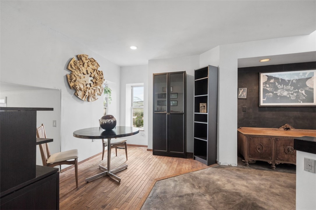 Dining area with a round table, hardwood floors, black cabinets, and an adjoining room with a carved sideboard.