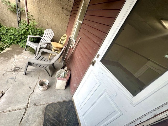 Home entrance with a white glass-panel door, concrete patio, and outdoor chairs.