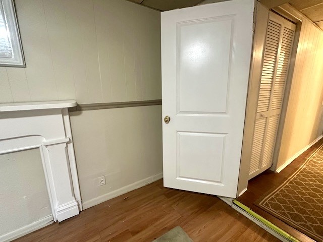 Unfurnished interior with wood floors, an open white door, and a louvered closet.