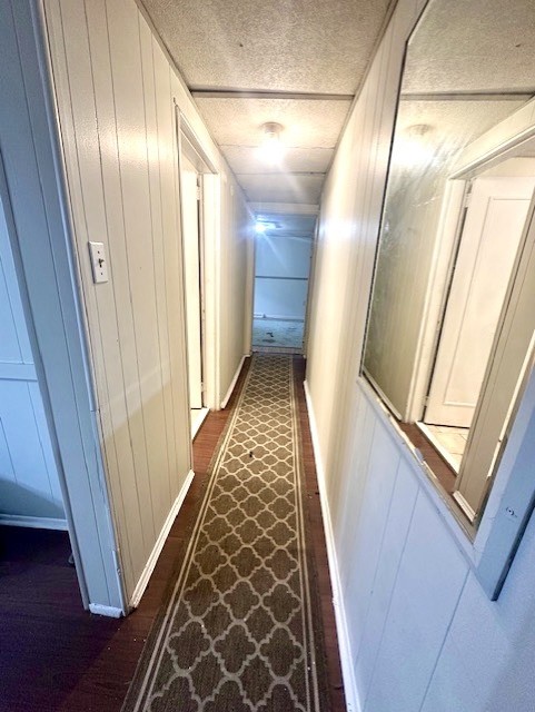 Narrow hallway with white paneled walls, a patterned runner, and an interior window.