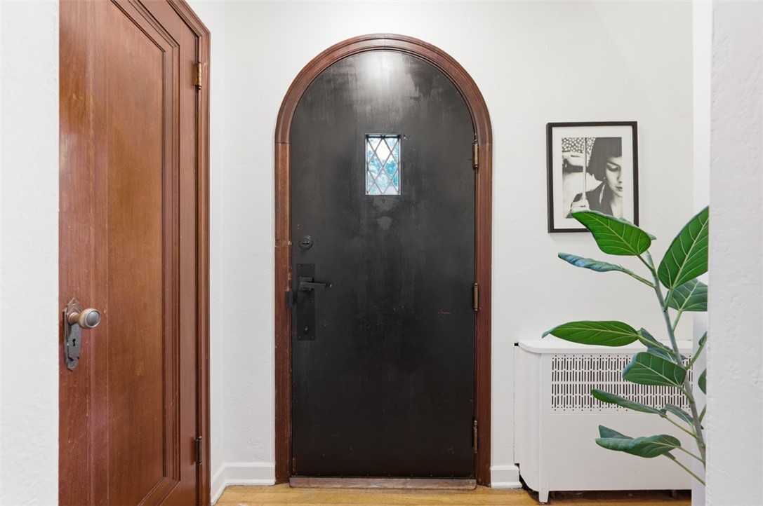 Entryway with a black arched front door, diamond-pattern stained glass, and wood trim.
