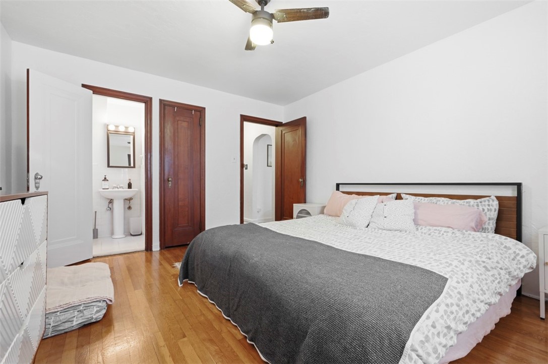 Bedroom with a large bed, hardwood floors, and an open doorway to a bathroom.