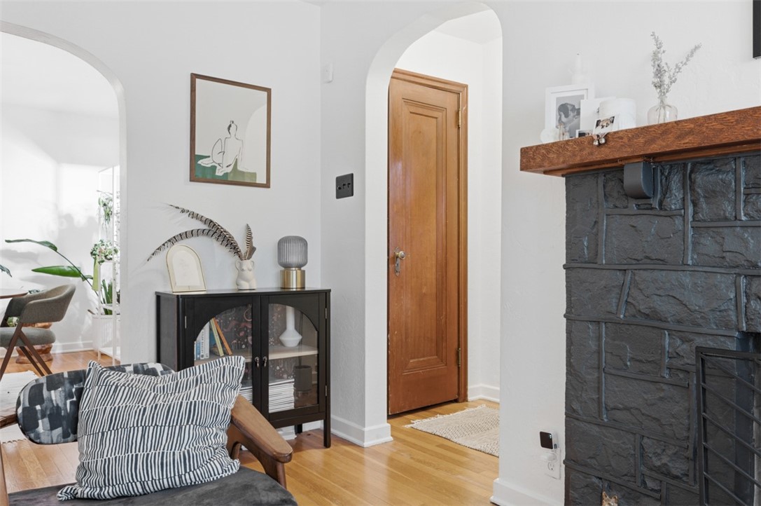 Furnished living room with a dark stone fireplace, hardwood floors, and arched openings.