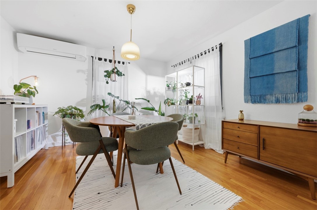 Dining room with a round wooden table, upholstered chairs, hardwood floors, and a blue wall hanging.