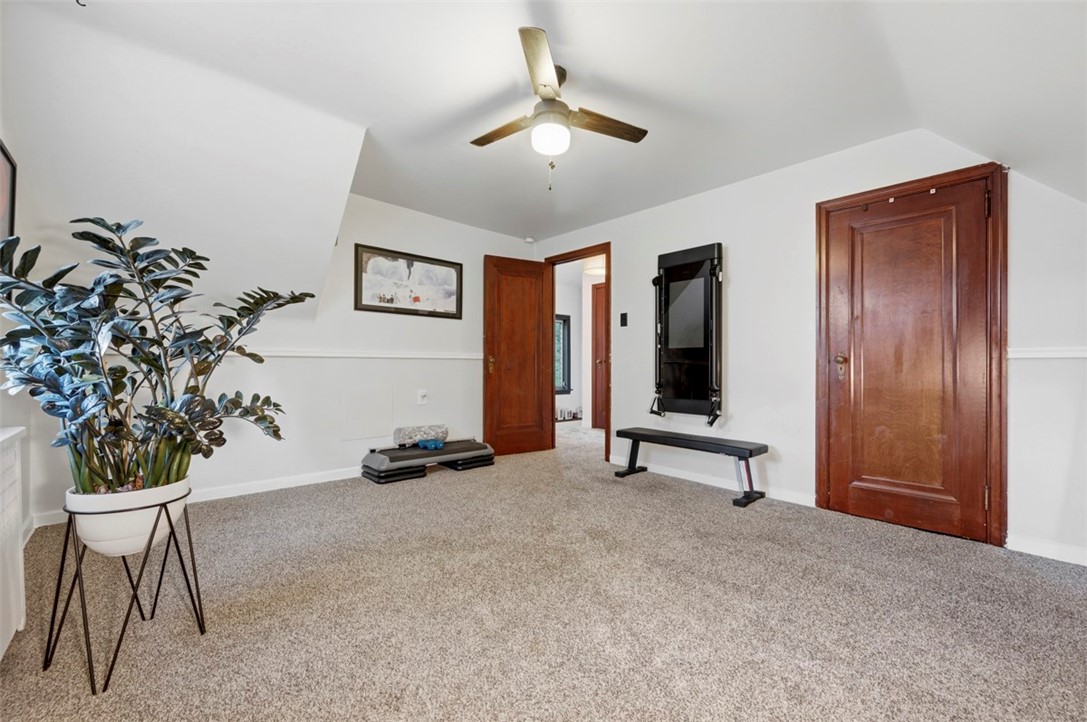 Carpeted exercise room with a ceiling fan, wood doors, and workout equipment.