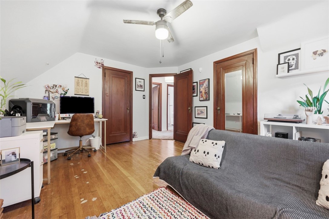 Furnished home office with hardwood floors, a desk, and a gray sofa.