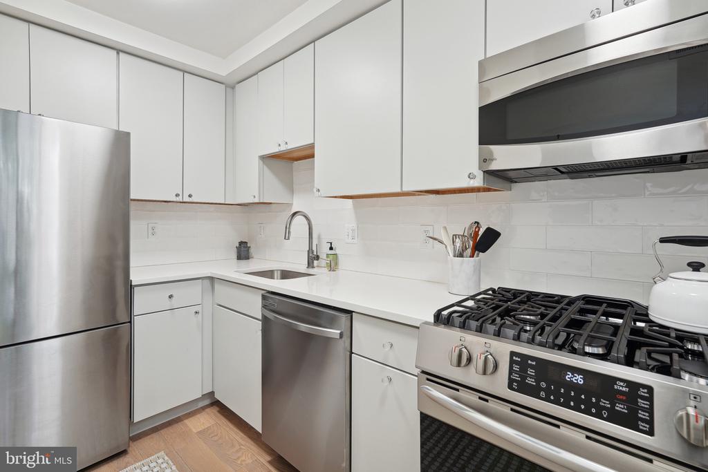 Modern kitchen with white cabinetry, stainless-steel appliances, and a gas range.