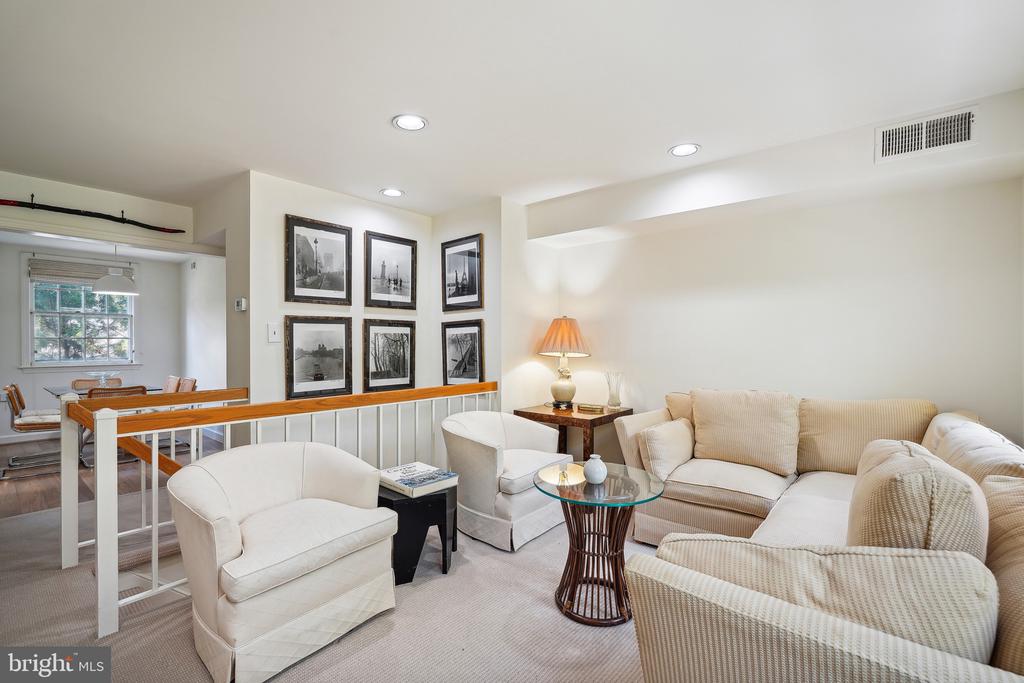 Living room with cream seating, a glass-top coffee table, and an adjoining dining area.