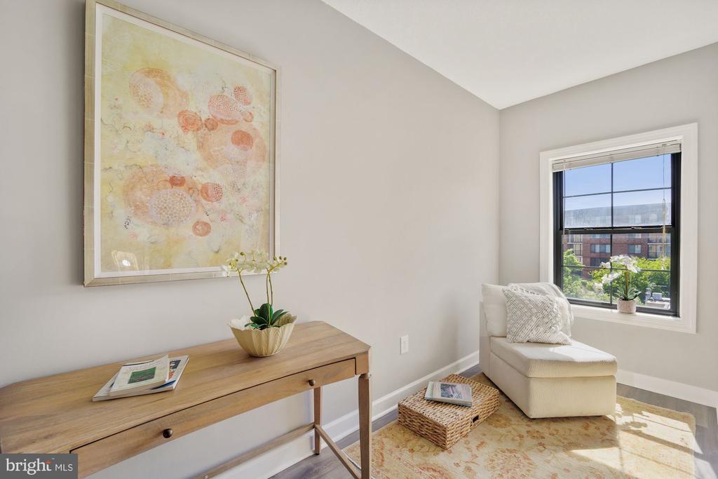 Bright sitting nook with a cream chaise beside a large window and wooden console table.