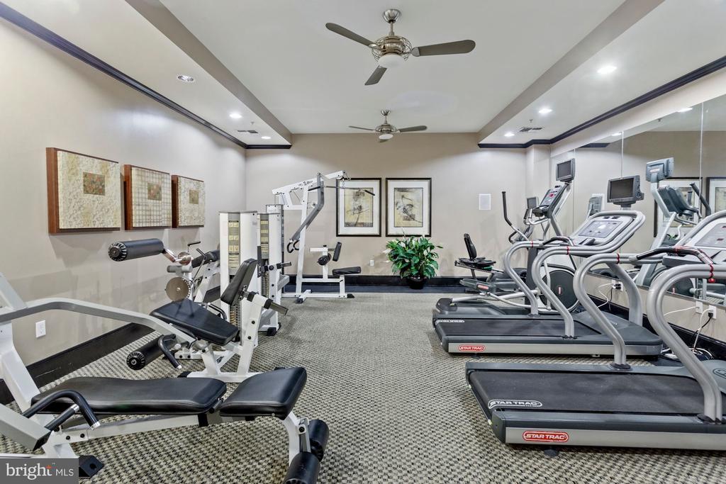 Fitness room with treadmills, mirrored wall, and weight-training equipment.