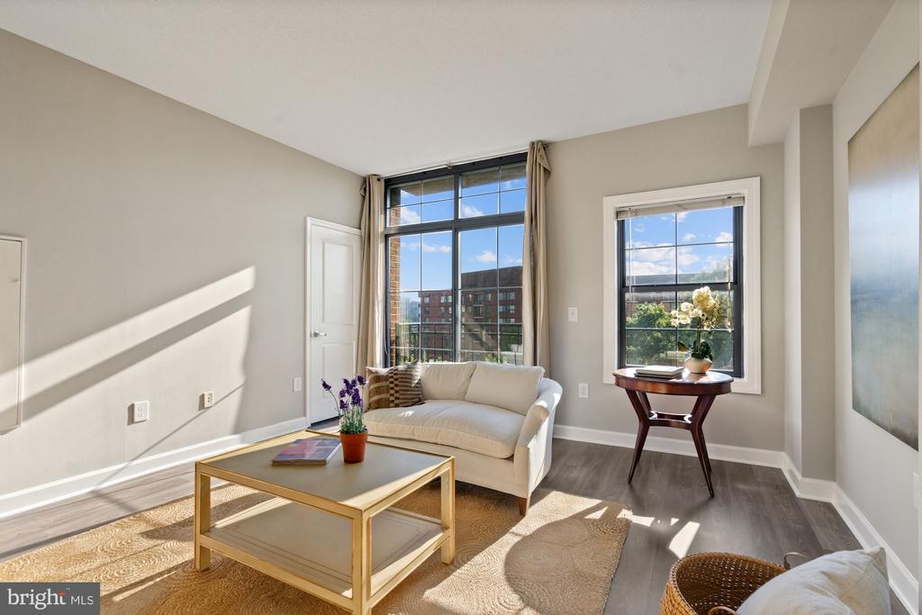 Staged living room with a white sofa, gold coffee table, and sunlit windows.