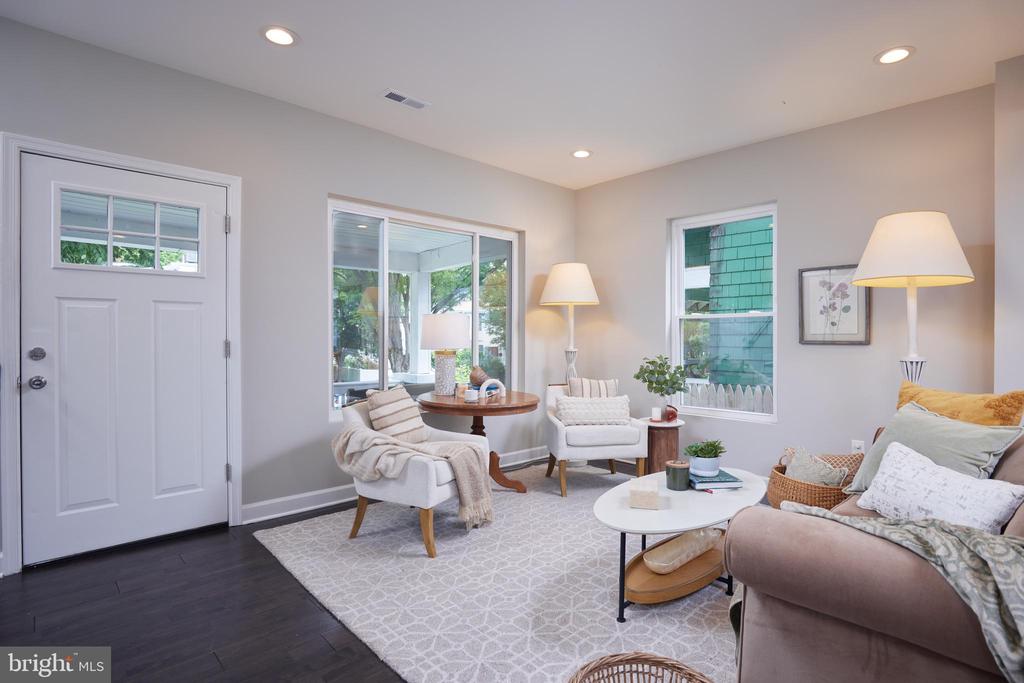 Furnished living room with two armchairs by large windows and a sofa beside a patterned rug.