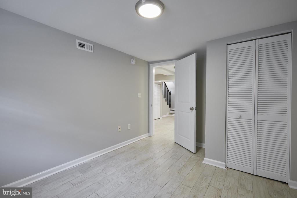 Empty bedroom with pale wood-look floors, a louvered closet, and an open door to the hallway.