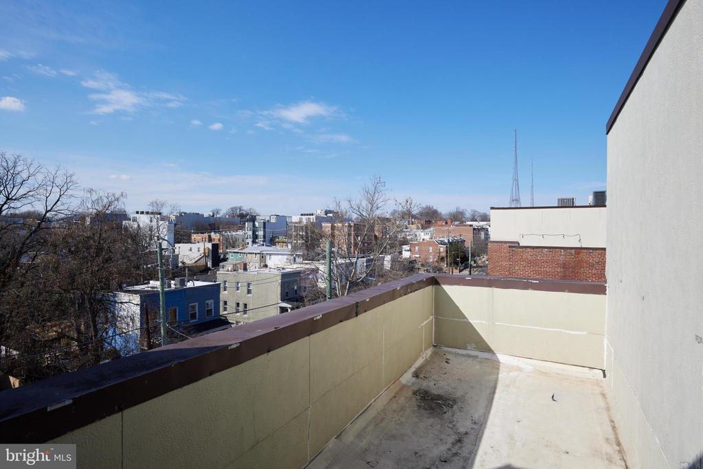 Rooftop terrace overlooking low-rise neighborhood buildings and bare trees.