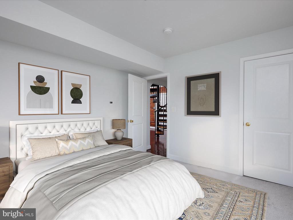 Staged bedroom with a tufted white bed, abstract wall art, and an open doorway to a spiral staircase.