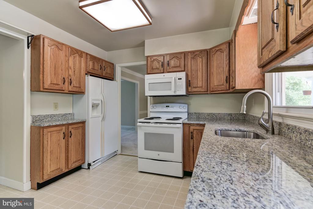 Kitchen with oak cabinets, granite countertops, and white appliances.