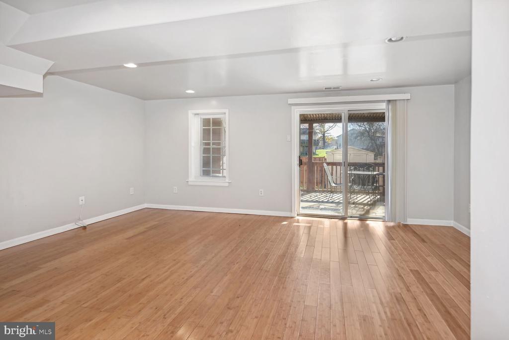 Empty living room with hardwood floors and sliding glass doors opening to a deck.