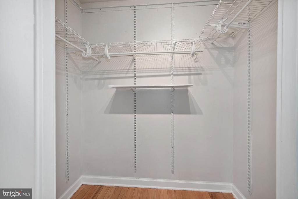 Empty walk-in closet with adjustable wire shelving and hardwood flooring.