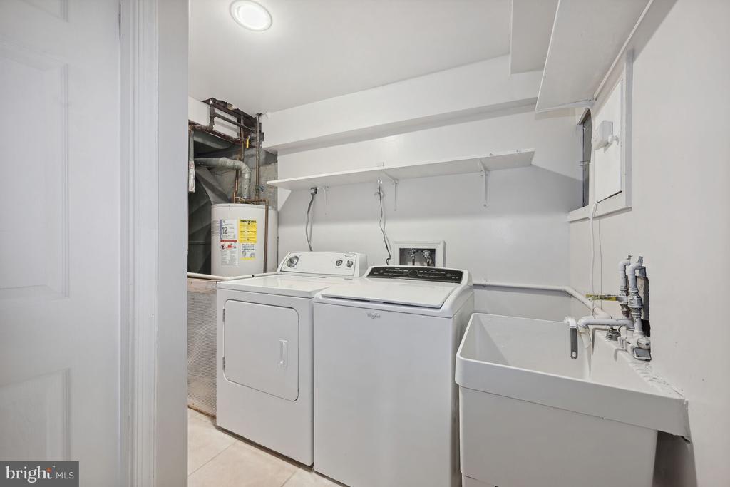 Laundry room with washer, dryer, utility sink, and wall shelving.