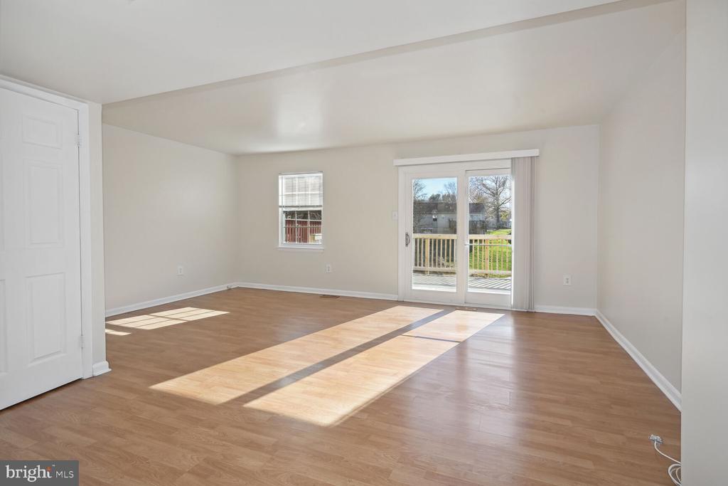 Empty living room with light wood flooring and sliding glass doors to a deck.