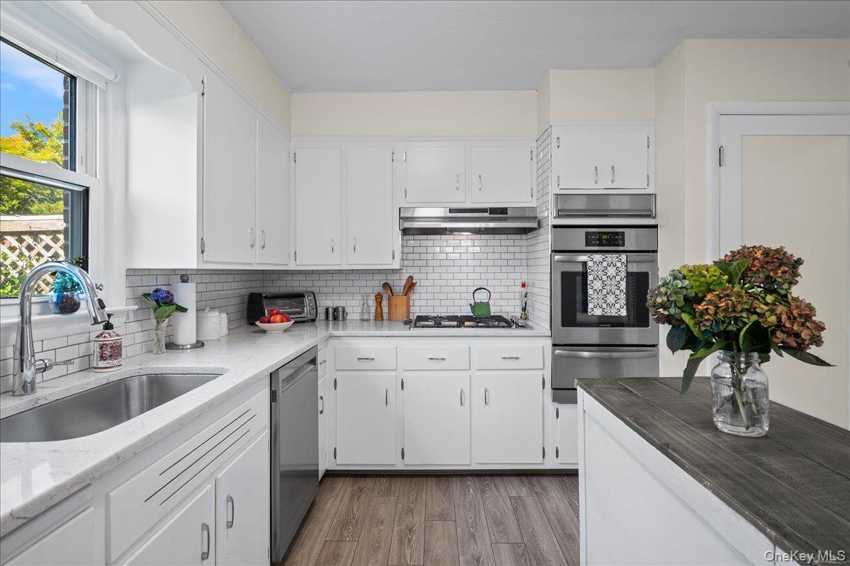 White kitchen with subway tile backsplash, stainless steel appliances, and a dark wood island.