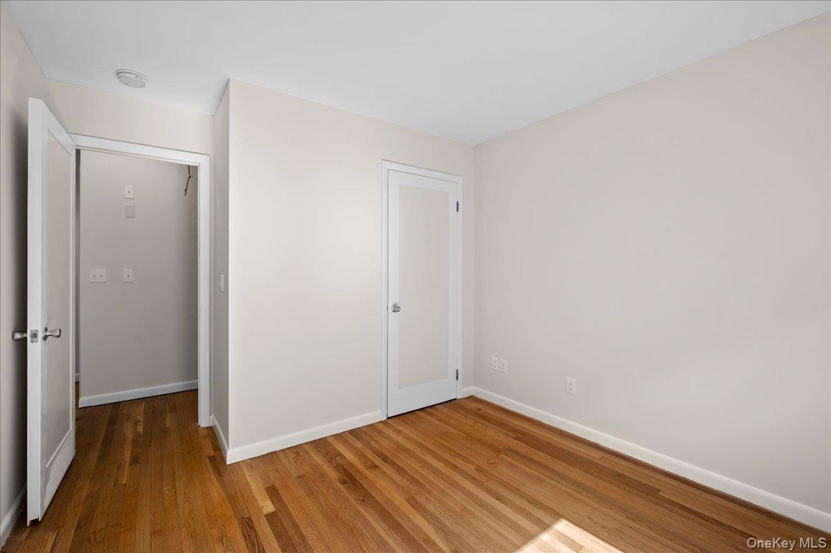 Empty room with hardwood floors, neutral walls, and two white doors.