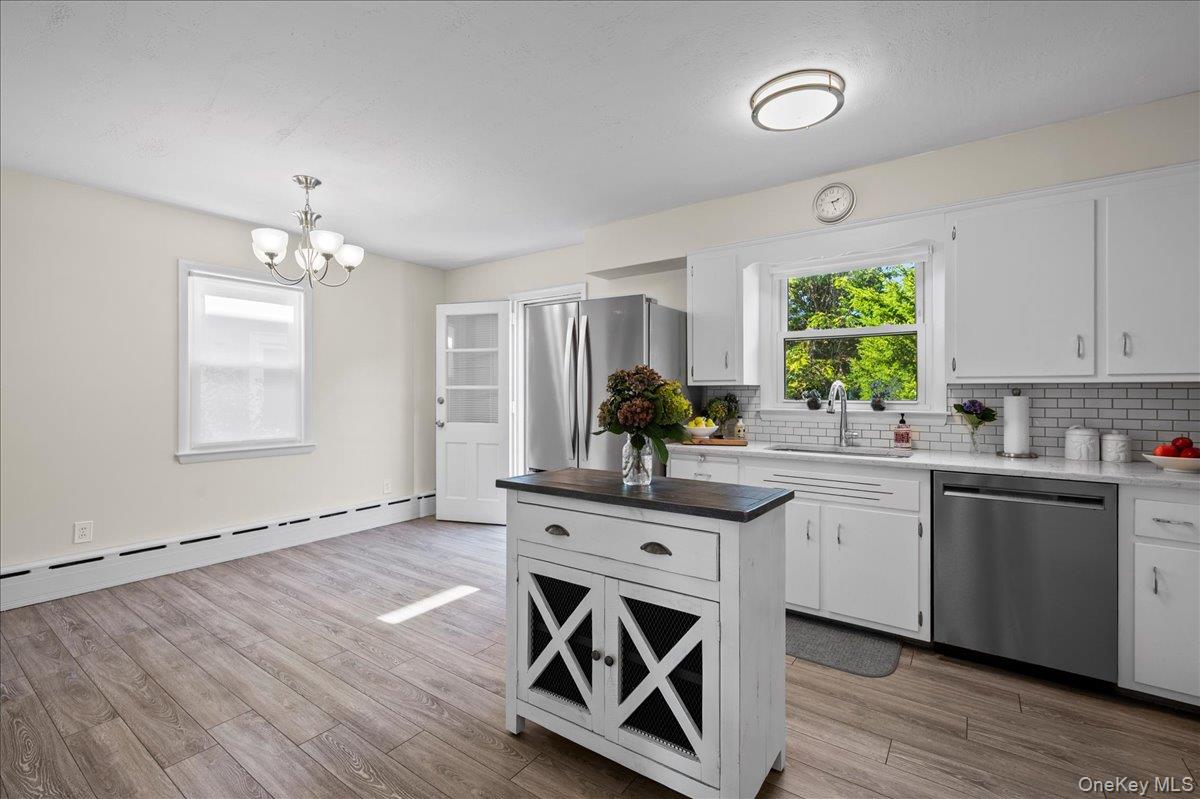 Kitchen with white cabinets, stainless appliances, and a central island with a dark countertop.