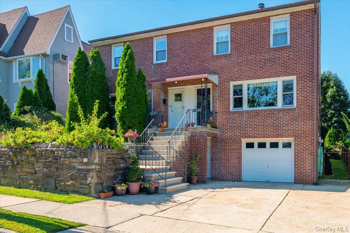 Two-story brick home with a raised entry, attached garage, and landscaped stone retaining wall.