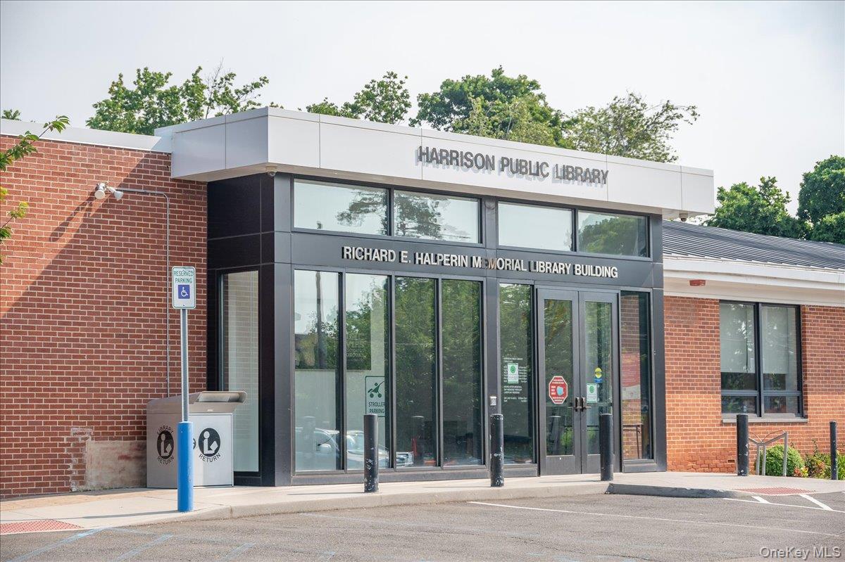 Harrison Public Library entrance with a red brick façade and dark-framed glass doors.
