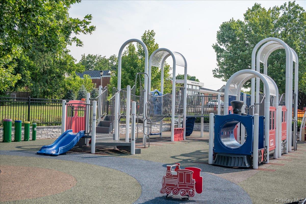 Outdoor playground with blue slides, climbing equipment, and a red play train.