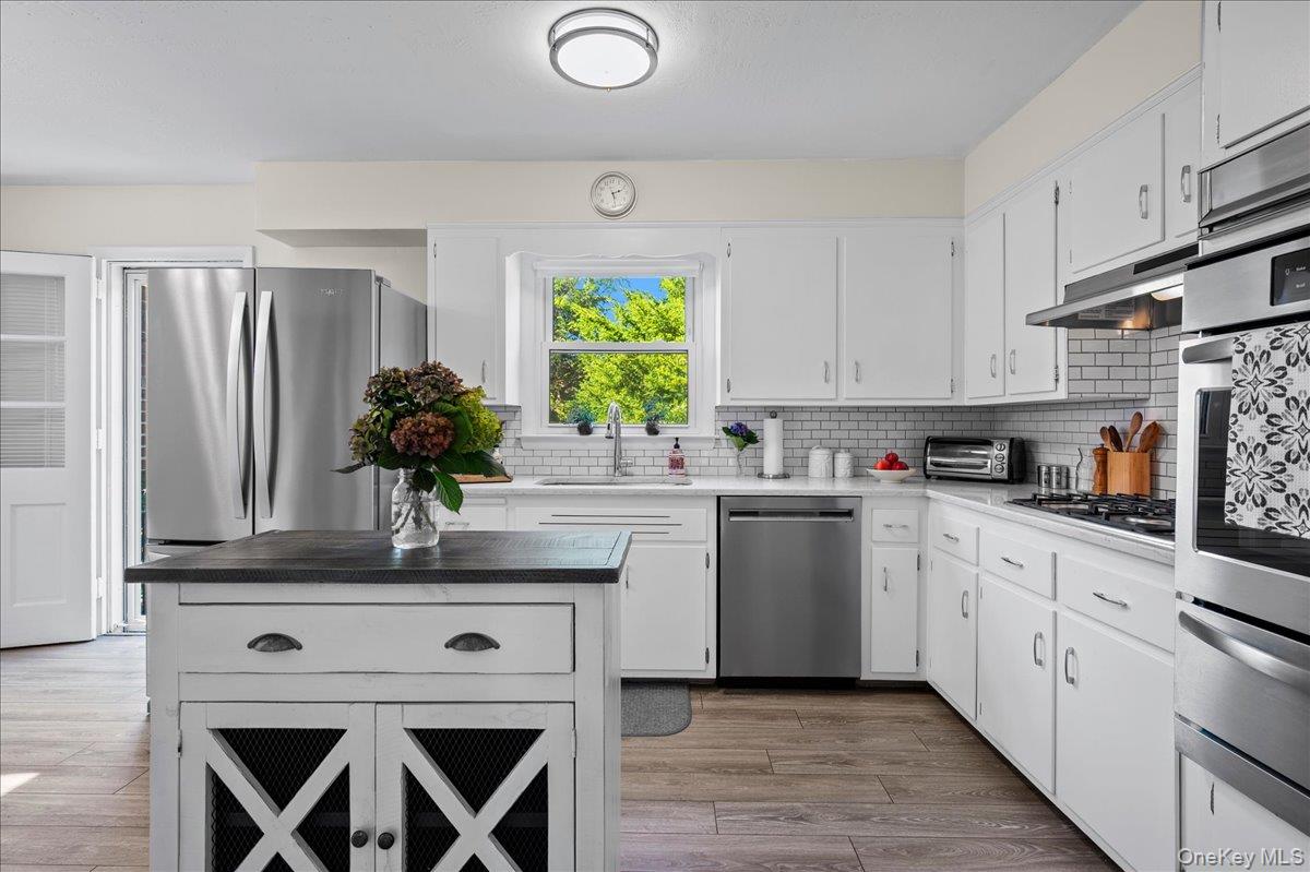 Kitchen with white cabinetry, stainless steel appliances, and a dark-topped island.