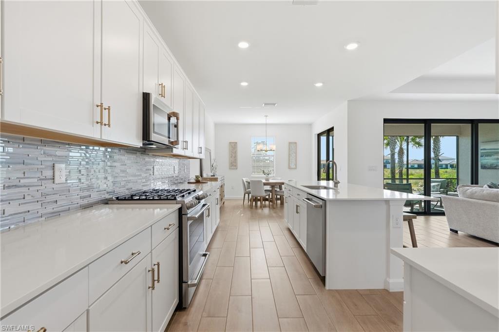 Open-plan kitchen with white cabinetry, a large island, and views through sliding doors to palms.