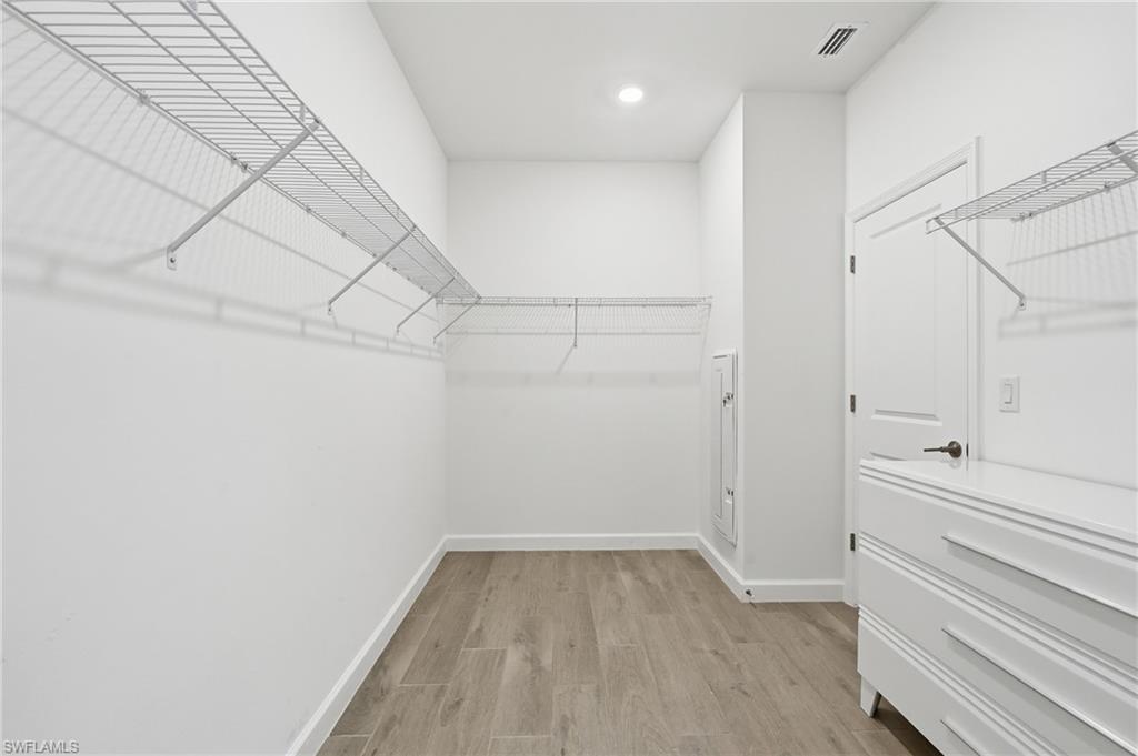 Walk-in closet with wraparound wire shelving, a white dresser, and wood-look tile flooring.
