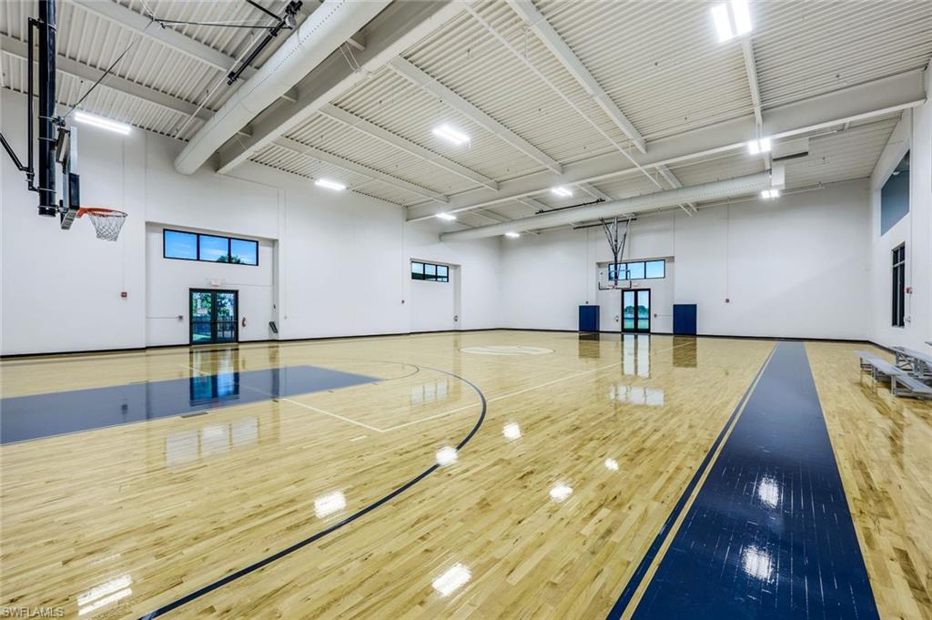 Indoor basketball court with a polished wood floor, blue markings, and two hoops.