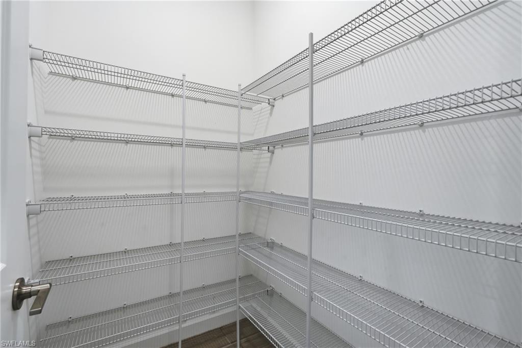 Walk-in pantry with extensive white wire shelving and dark wood-look flooring.