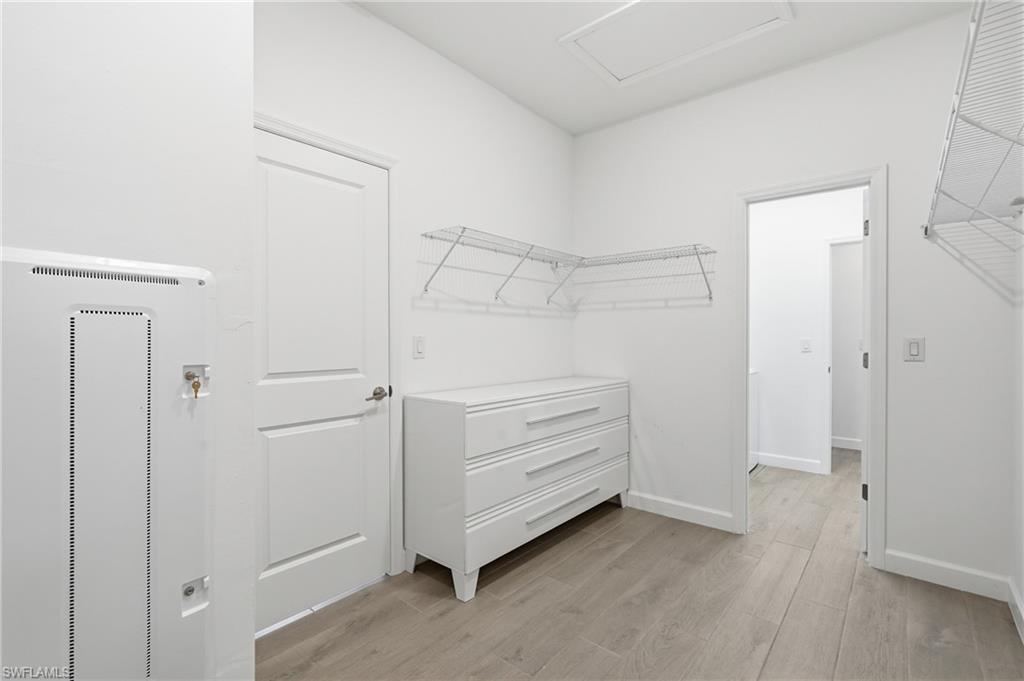 Walk-in closet with a white dresser, wire shelves, and light wood-look flooring.