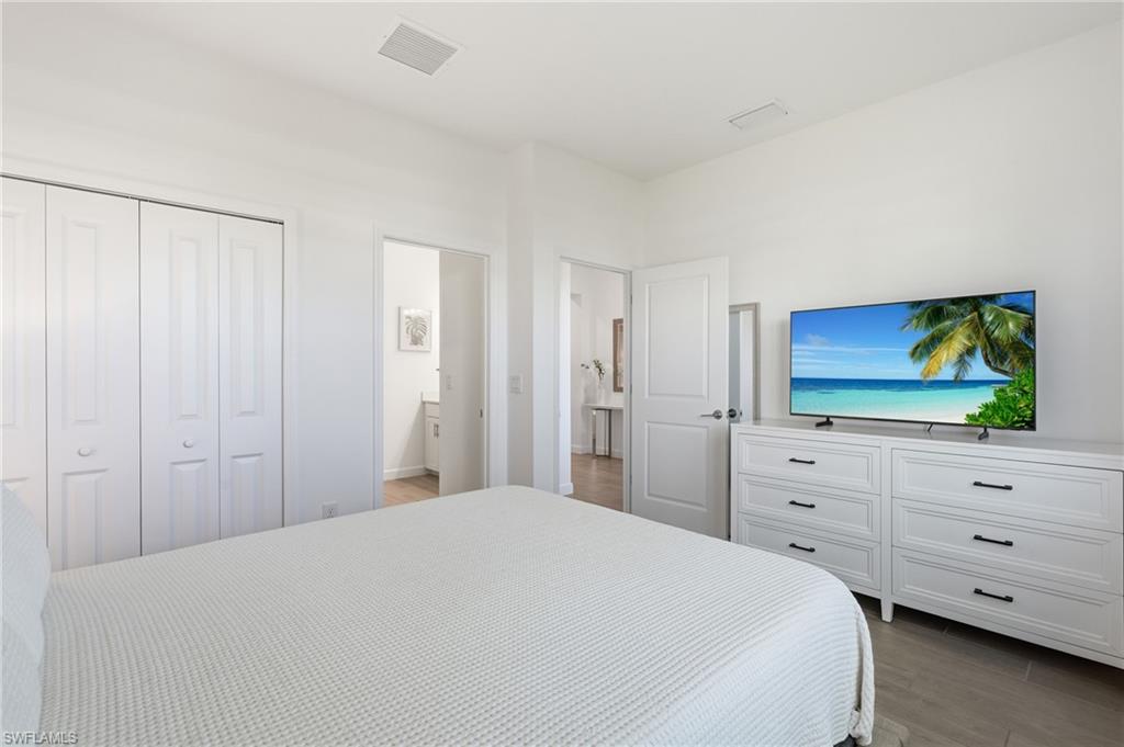 Bright bedroom with white closet doors and a TV on a long dresser.