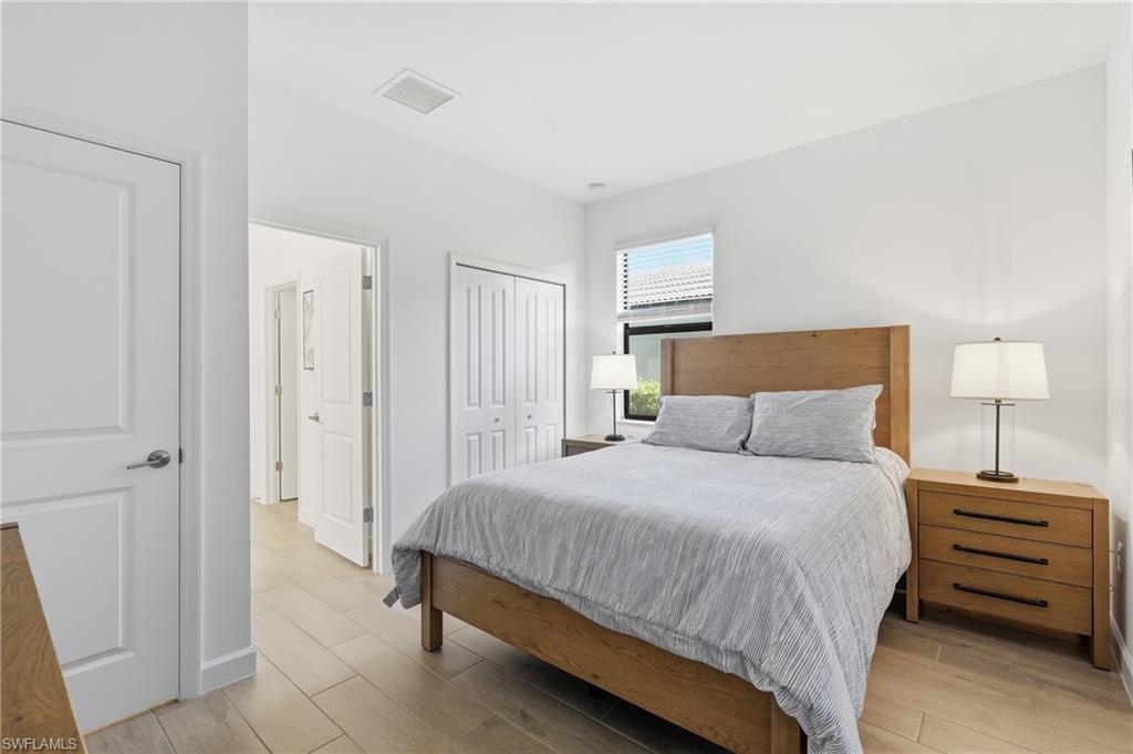 Bedroom with gray bedding, a wood bed frame, matching nightstands, and light tile flooring.