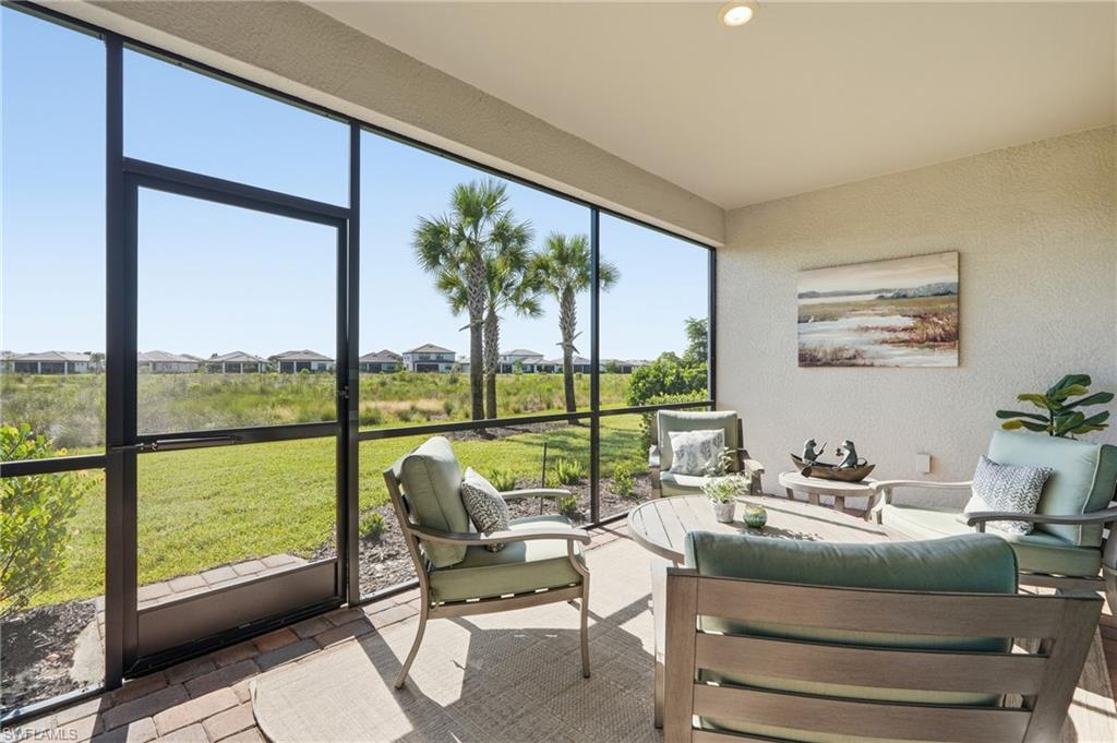Covered lanai with cushioned seating overlooks a grassy yard and palm trees.