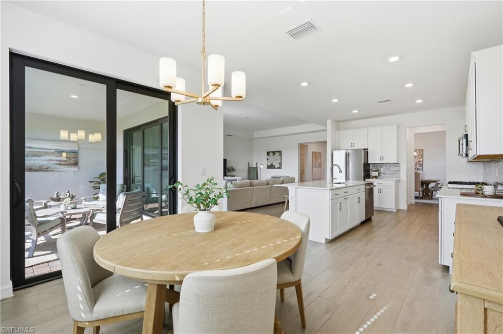Open dining room with a round wood table, white kitchen island, and sliding doors to a patio.