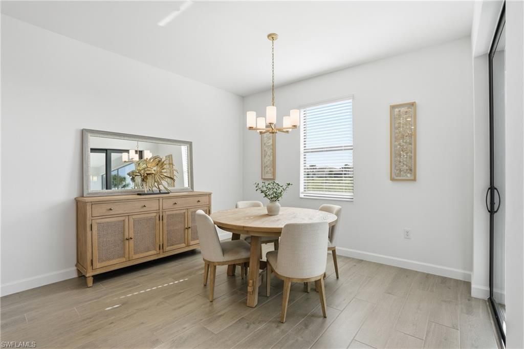 Dining room with a round wooden table, upholstered chairs, mirrored sideboard, and chandelier.